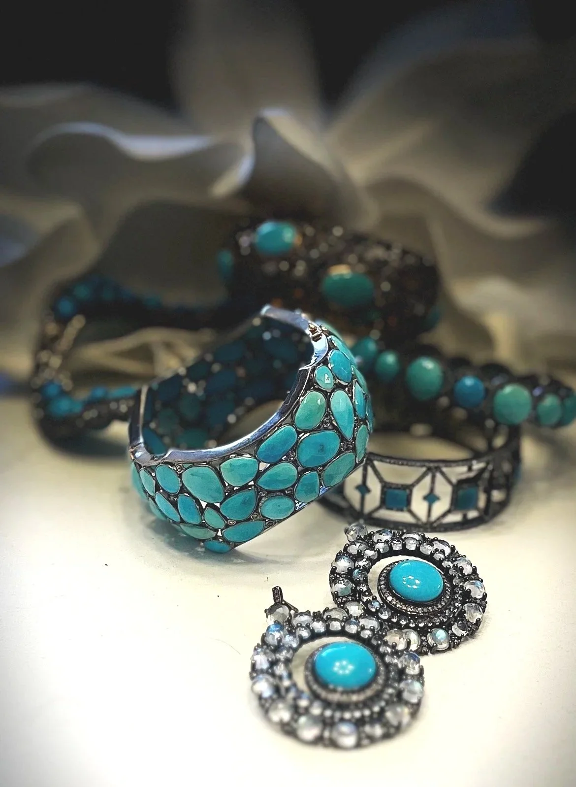 Collection of jewelry including a turquoise and silver ring, turquoise earrings, and turquoise and silver bracelet, arranged on a surface with a blurred background.