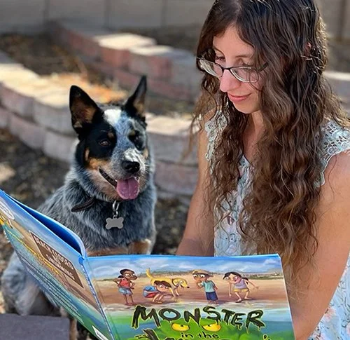 Designer Maria DeCerce reading a book she illustrated to her dog Lana