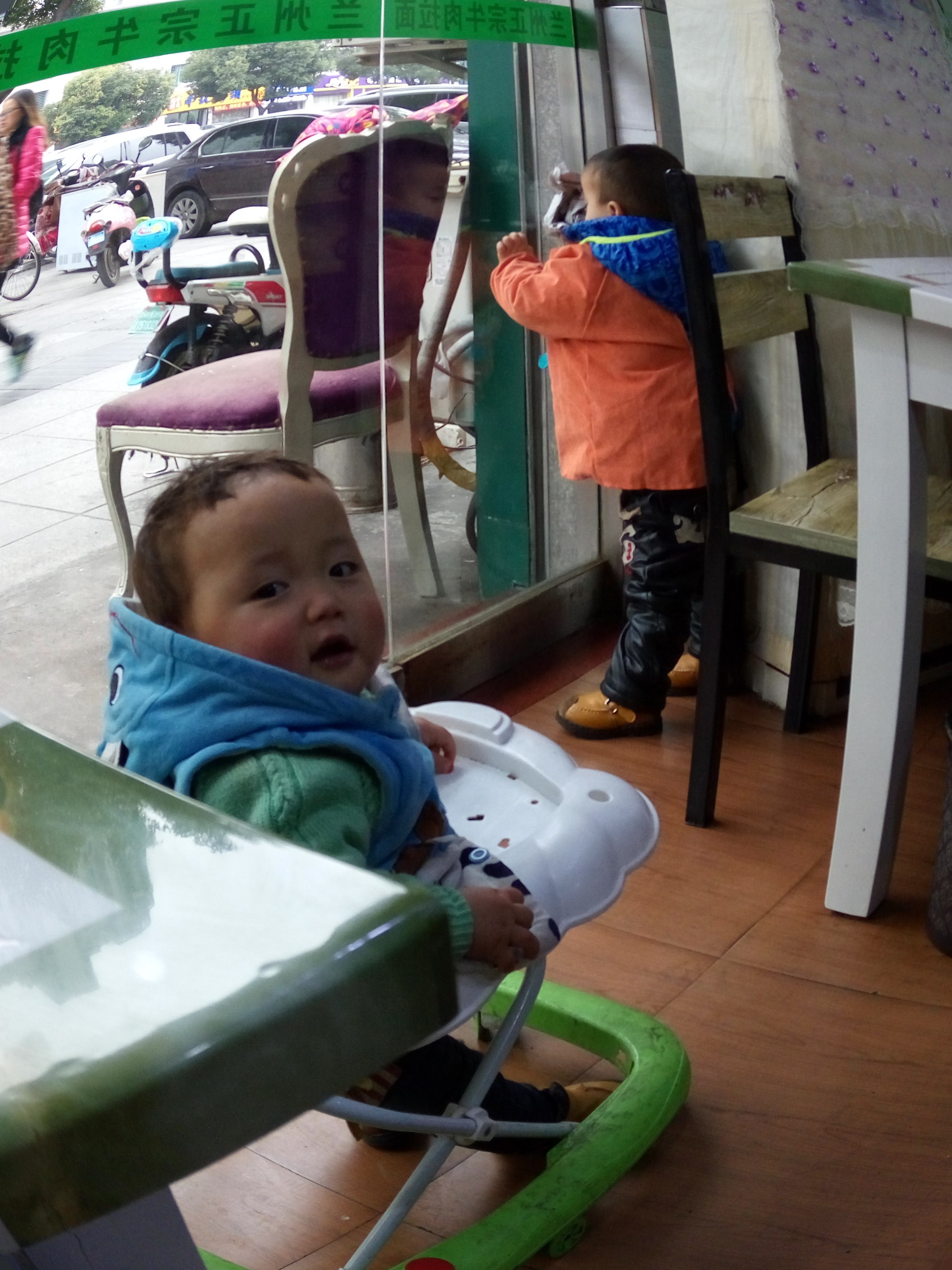 The noodle maker’s baby bounces about while the owner’s son looks out.