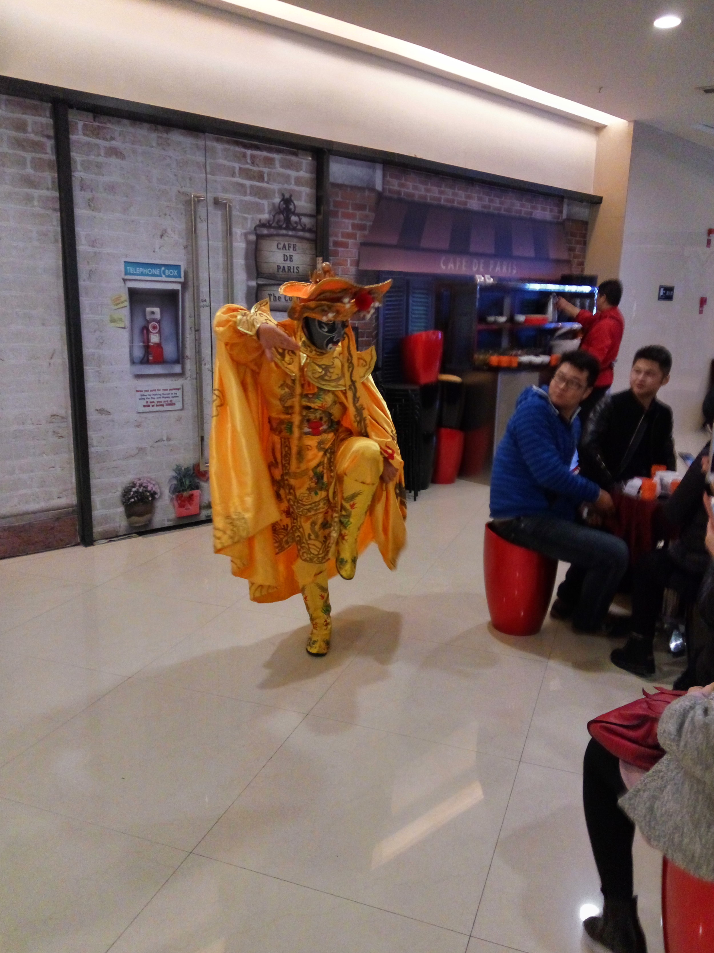  Outside of a mall restaurant a man puts on a show for the customers.