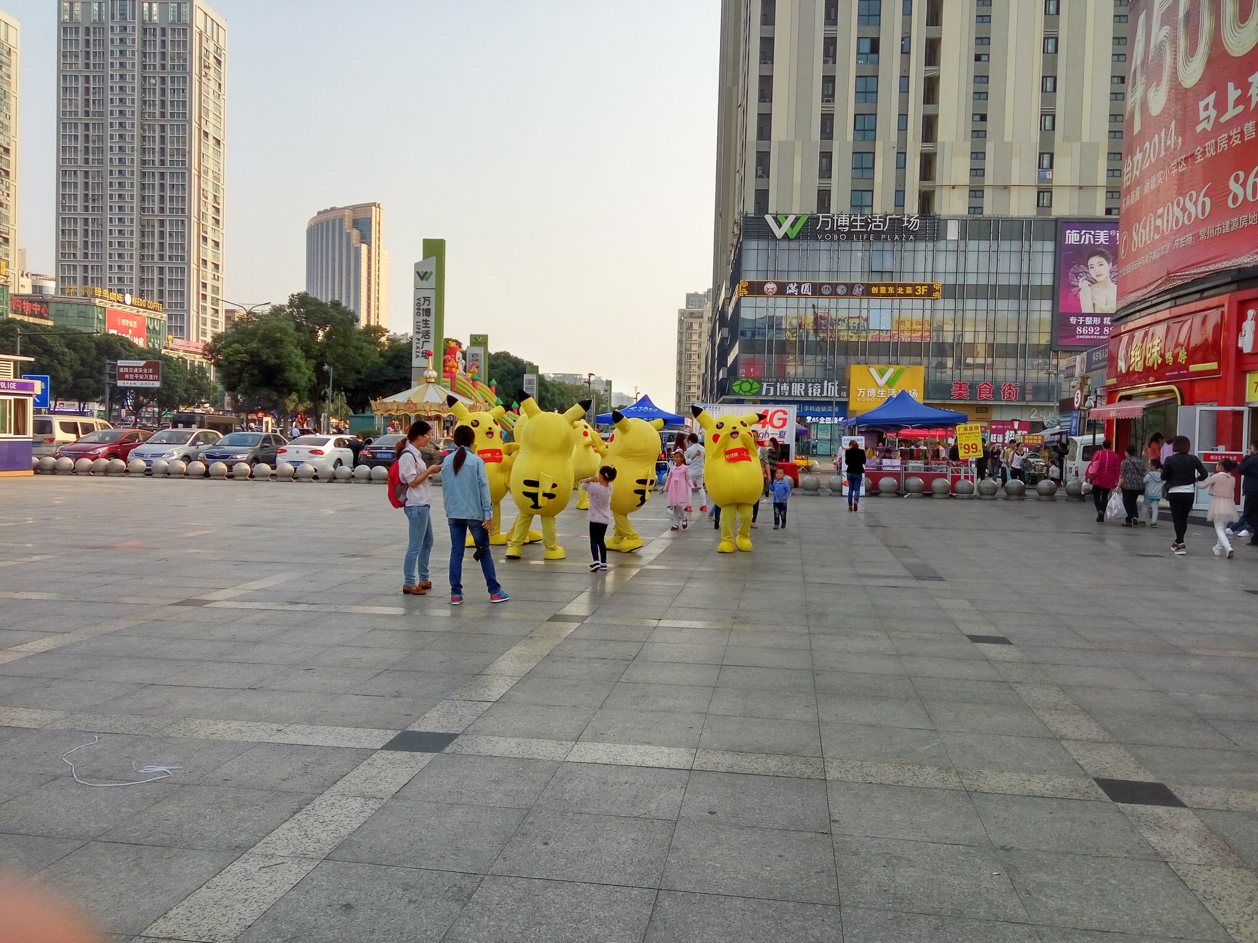 A gaggle of Pikachus entertain a few children.
