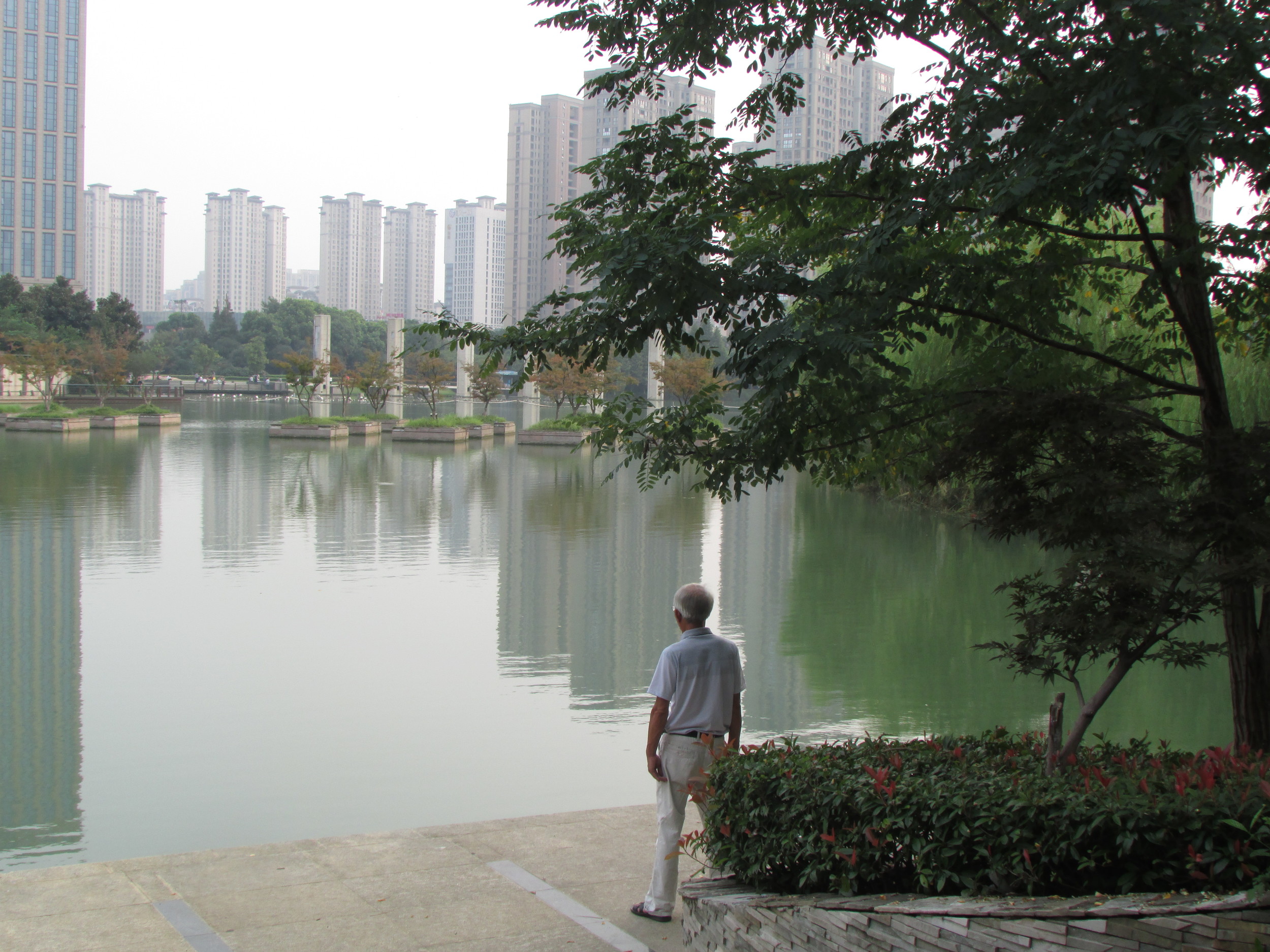 An old man stands in concentration so rigorous that it makes him look sturdier than the skyscrapers.