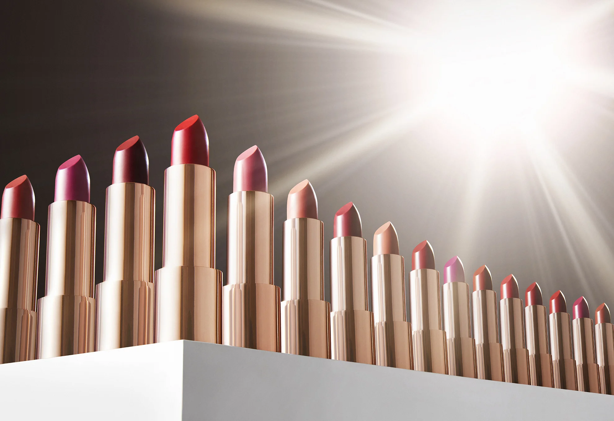  Still life photographer in London Josh Caudwell shoots creative make up product photography. Beauty cosmetics photography of lipsticks products lined up in a row. Metallic shiny cosmetics photographer based in London, Paris and New York NYC. 