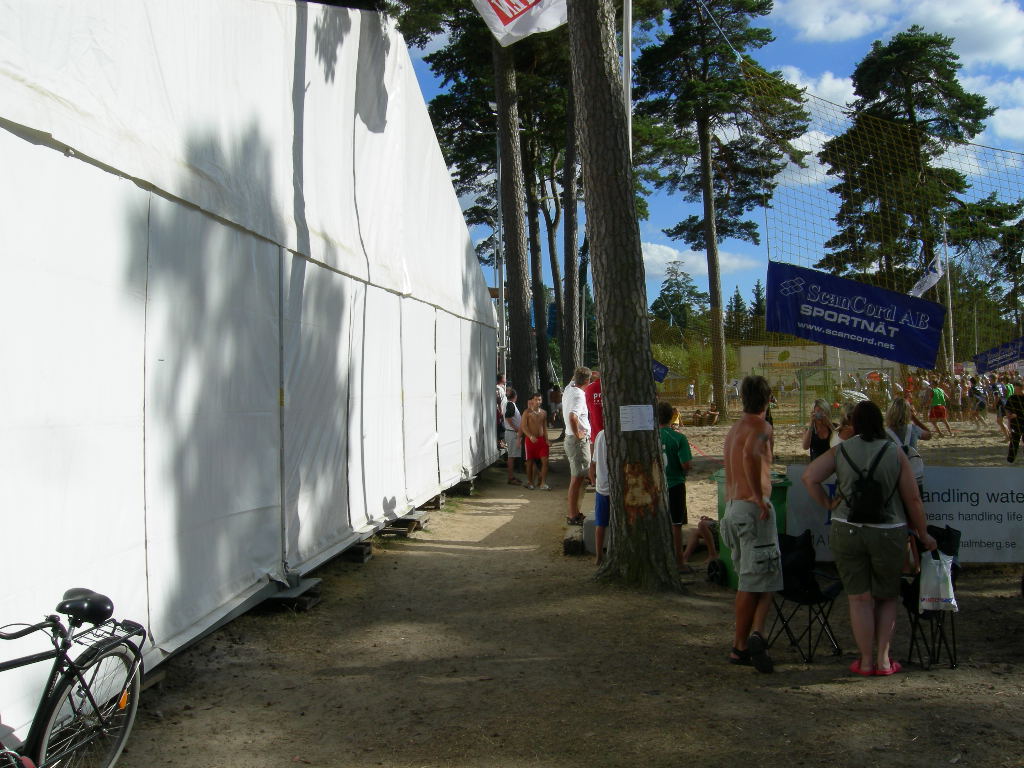 .... där jag lyckats pricka in den årliga beach-volleyboll turneringen vid mer än ett tillfälle. Denna gång var det en gripen snattare på sportbutiken som vi skulle ta hand om. Mina turnéer runt om i landet har ibland av en slump visat sig överensstämma med vissa artisters program. En sommar så råkade jag pricka in Ulf Lundells spelningar i ett flertal orter. Har glömt vad Ulf Lundell kallade sin turné. Min kallade jag för "Våldsamt motstånd 1999". Ulf Lundell åkte runt och spelade. Jag åkte runt och fick ovanligt många våldsamma motstånd. Vid en danstillställning i skogen utanför en liten ort i Värmland var ett av flera tillfällen. Alla verkade känna alla och vem jag var spred sig snabbt. En full, stor Hellyhansentröjeförsedd man kom fram till mig puttade till mig i bröstet och sade "Du Stockholmarn - är du bra på att slåss!". Jag hade definitivt ingen lust att slåss. Ju mindre orter, ju längre avstånd till förstärkning, ju mer smidiga är kollegorna. Men, ibland hjälpte det inte. Om vi återgår till bilden i Åhus så är de skogsbeklädda sanddynorna en bit därifrån mycket vackra och fördelaktiga att slå upp ett tält. Men denna gång fick jag bo hos kollega.