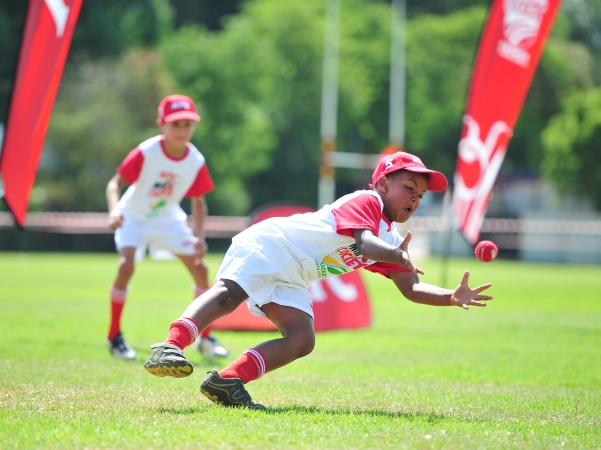A young boy dives for a catch while competing in KFC Mini-Cricket. The organisation provides the first steps into cricket, not only for young boys and girls, but for coaches as well.