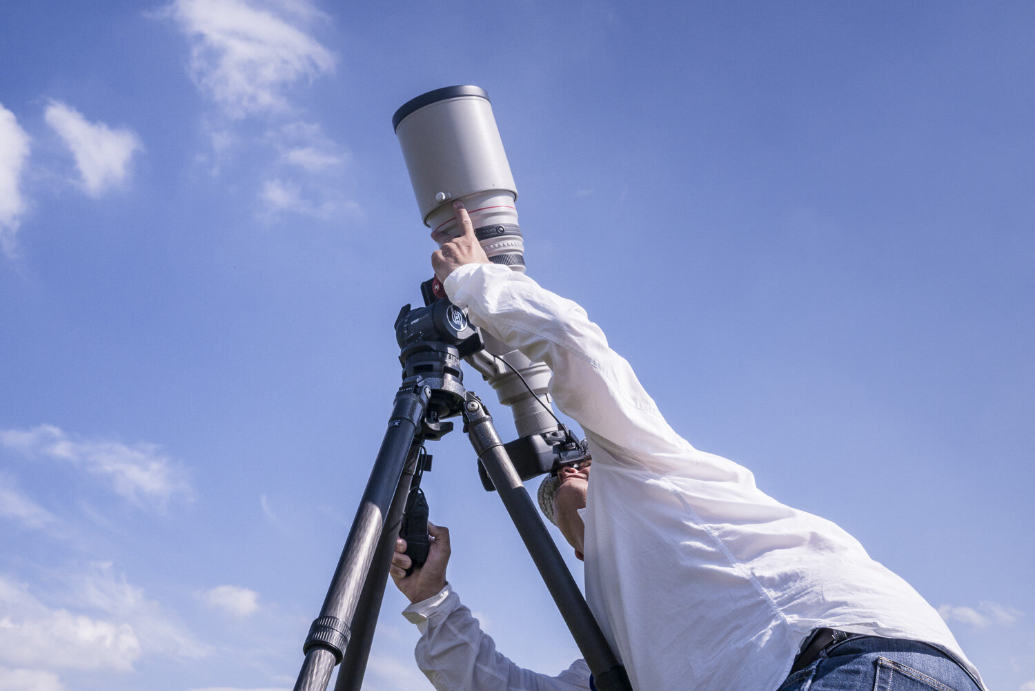 Un photographe spotter scrute le ciel avec un téléobjectif