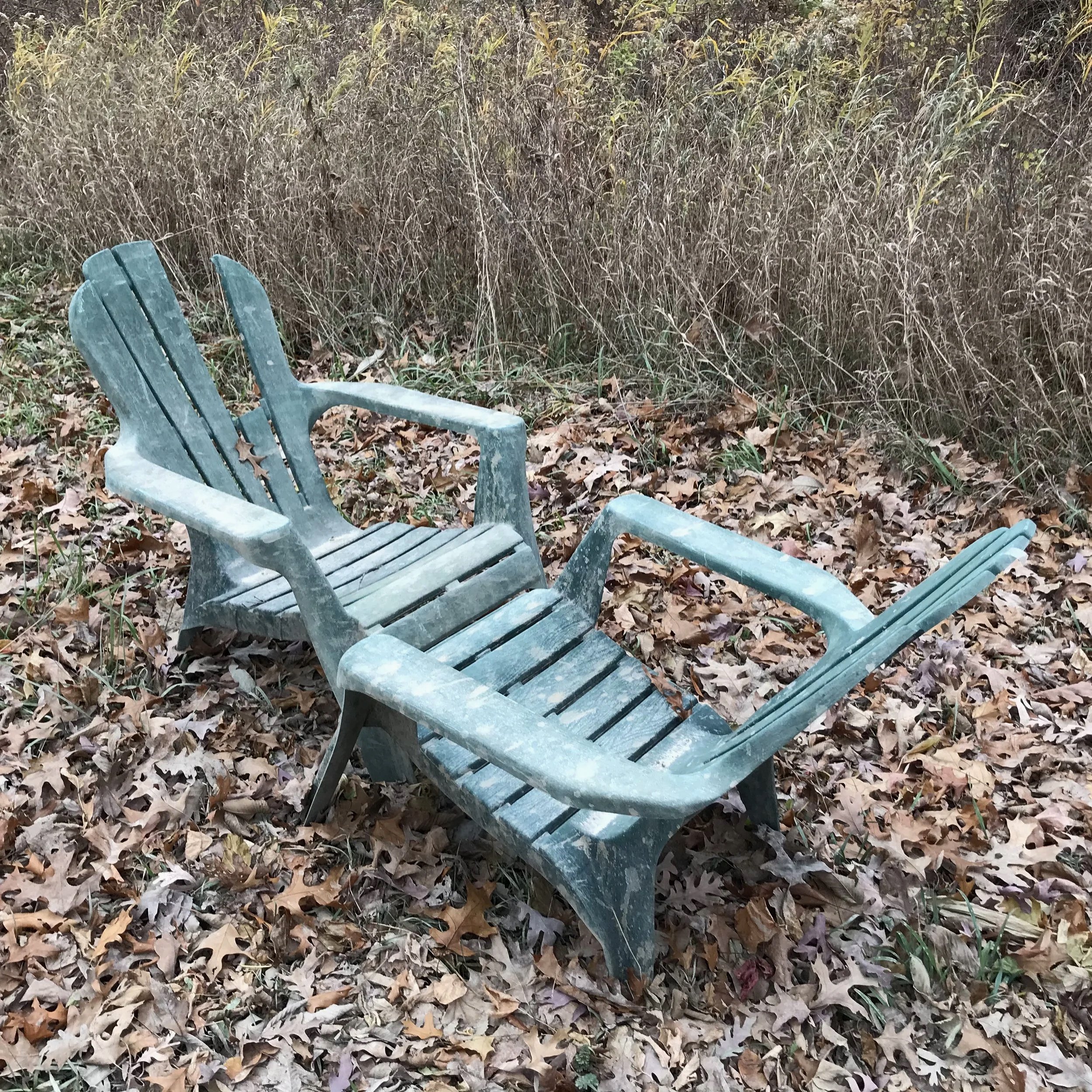 Adirondack Rack , 2026. Plastic Adirondack chairs. Huron-Manistee national Forestland, MI. Two plastic Adirondack chairs, typically associated with domestic leisure spaces such as patios and backyards, were found in a clearing in the woods, presum
