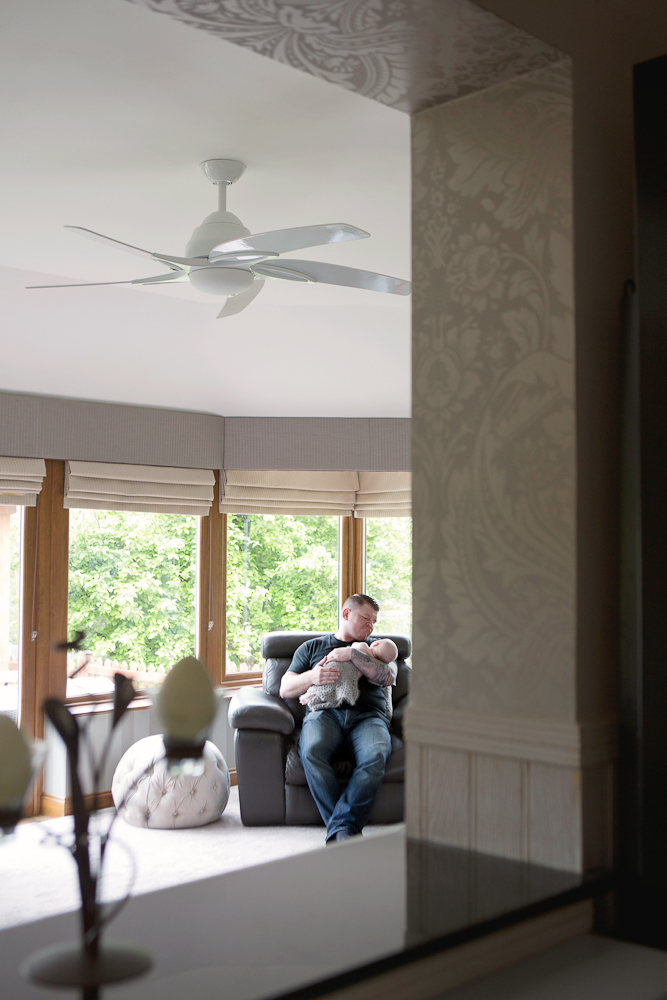 dad holding newborn baby in living area at home