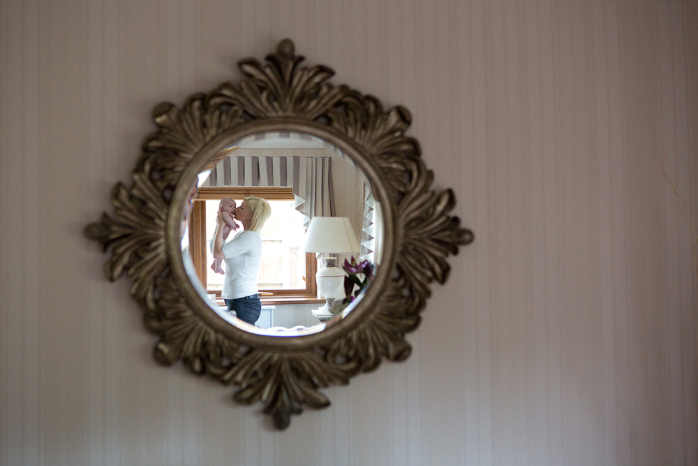 mum holding baby girl up in mirror