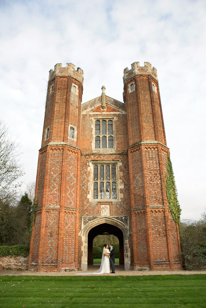 Bride and groom under tower at Leez Priory