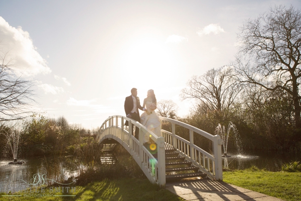 bride and groom walking over bridge with sun