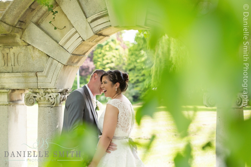 bride and groom laughing under arch