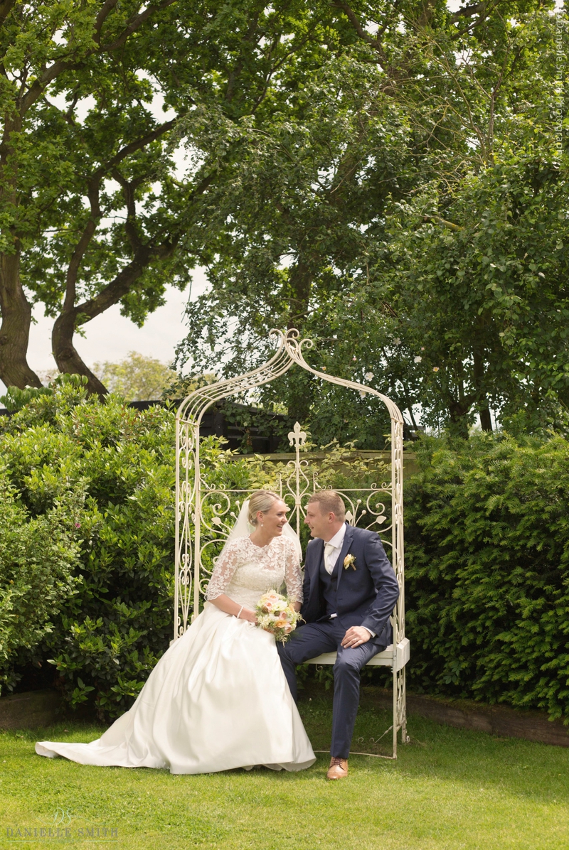 bride and groom sitting on ornate bench at maidens barn wedding