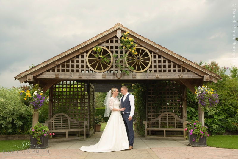 bride and groom standing by wooden structure - maidens barn wedding