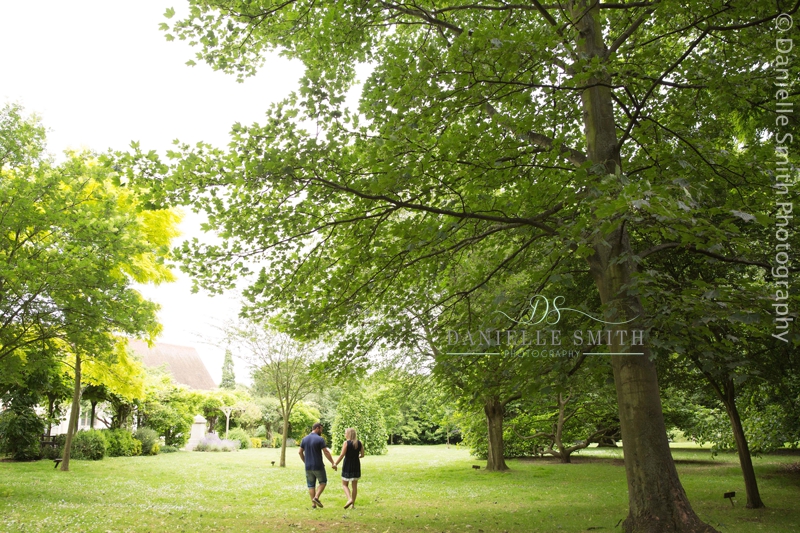 couple walking under tree in park