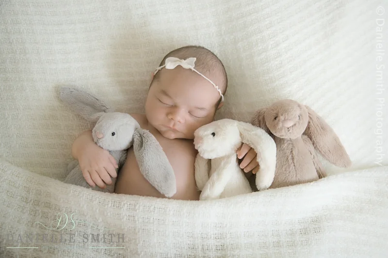 baby girl cuddling her bunnies in bed