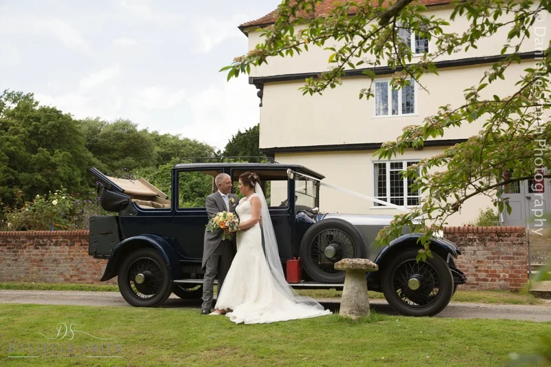 bride and groom with vintage car outside houchins wedding venue