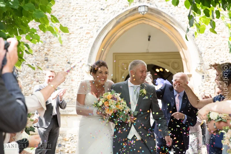guests throwing confetti over bride and groom outside church