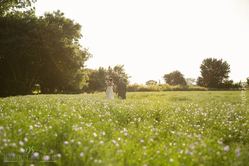 bride and groom walking through flower field at houchins