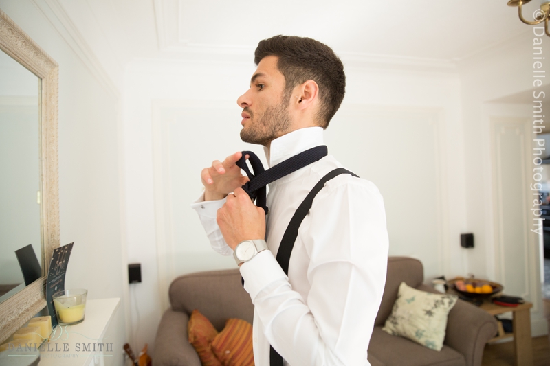 groom doing his tie in mirror - old brook barn wedding