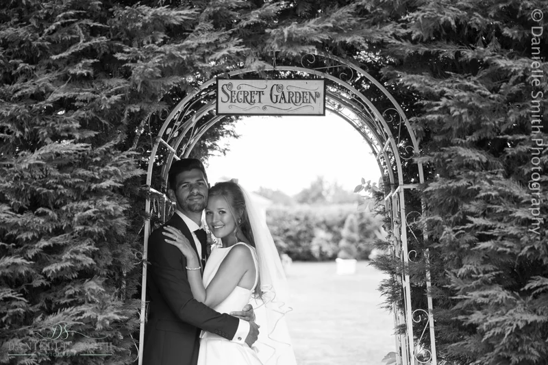 bride and groom under secret garden arch
