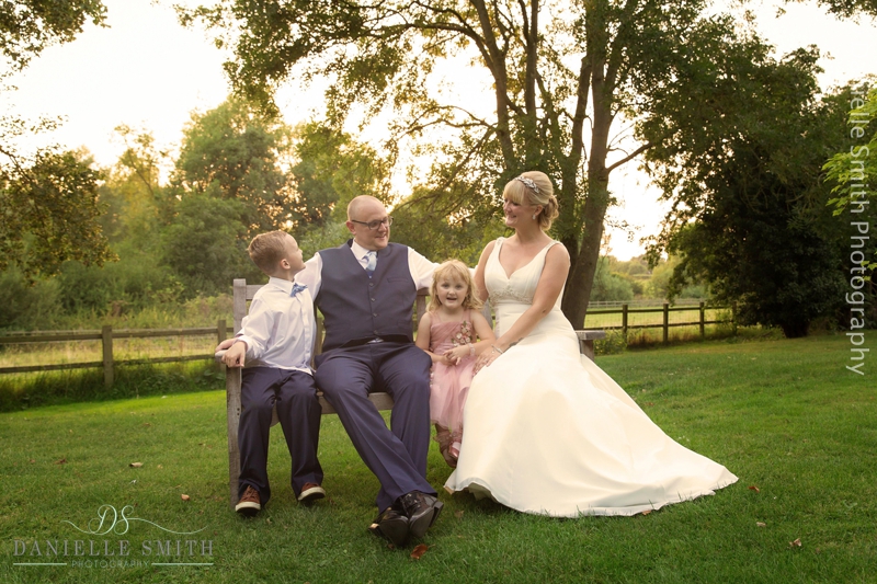 bride and groom and kids sitting on bench