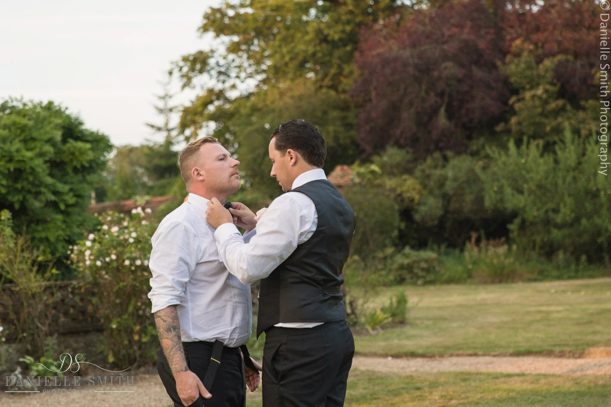 groom helping best man with tie