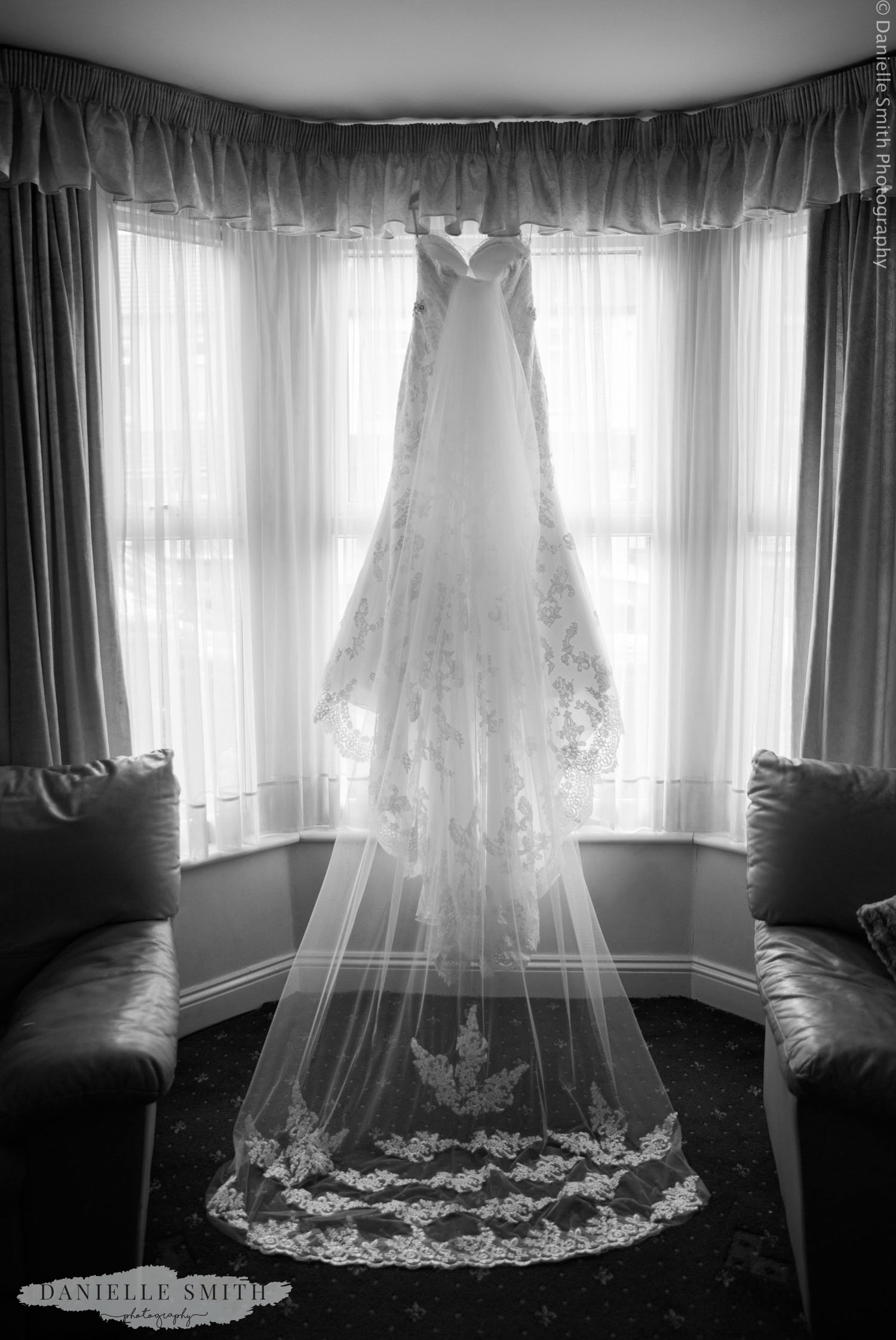 wedding dress and veil hanging in window
