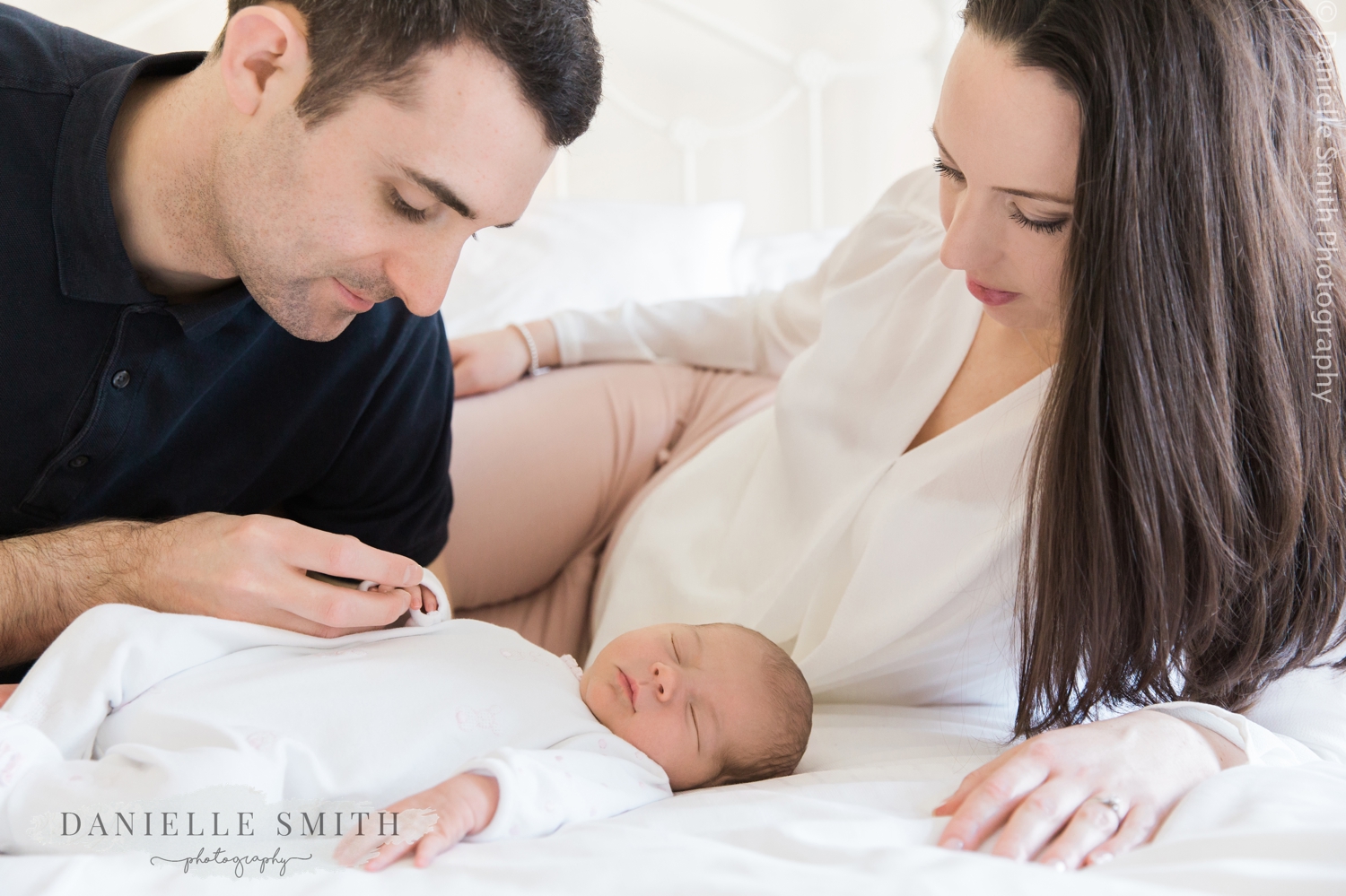 mum and dad laying on bed with newborn baby