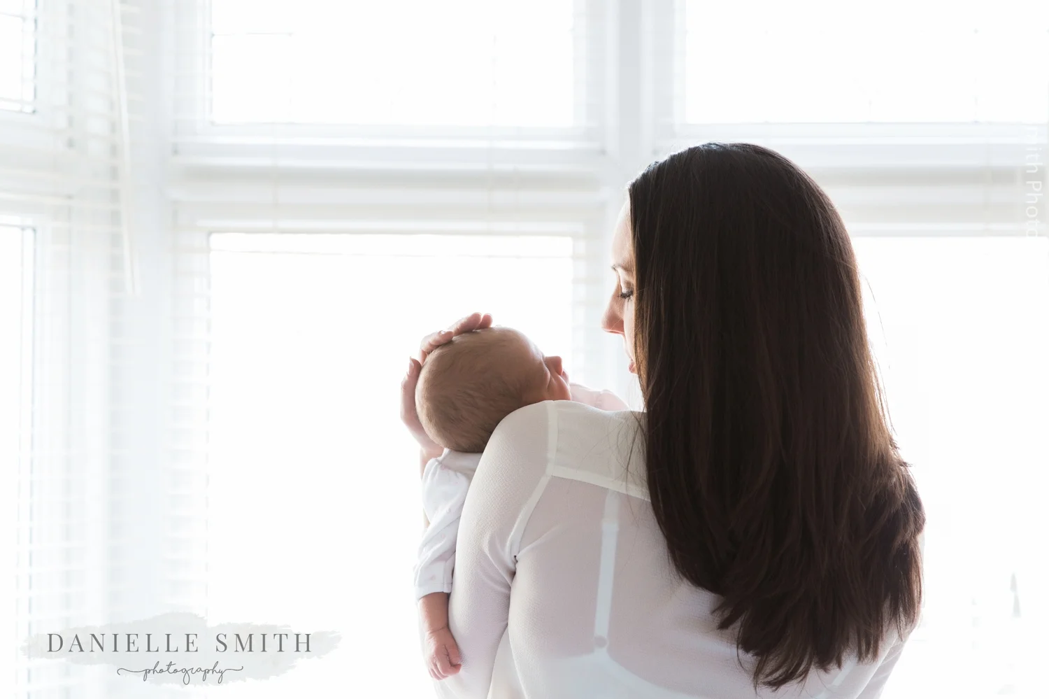 mum holding newborn baby in front of window - natural newborn photography