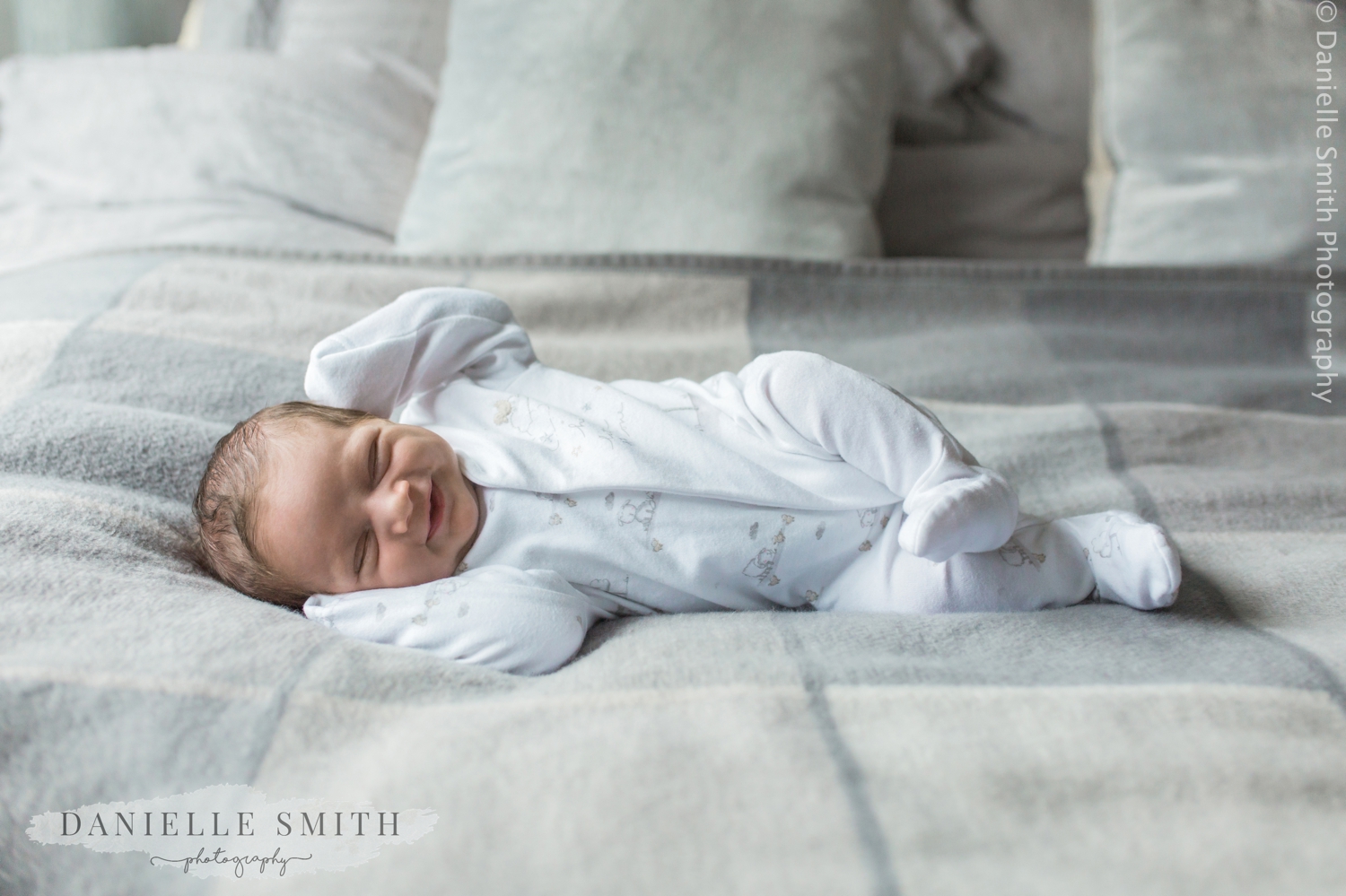 newborn baby laying on bed at home