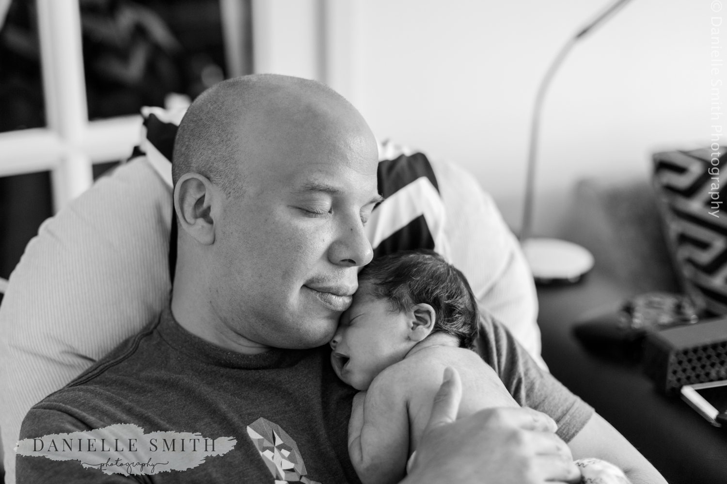 dad sleeping with baby in arms - newborn lifestyle photo shoot colchester