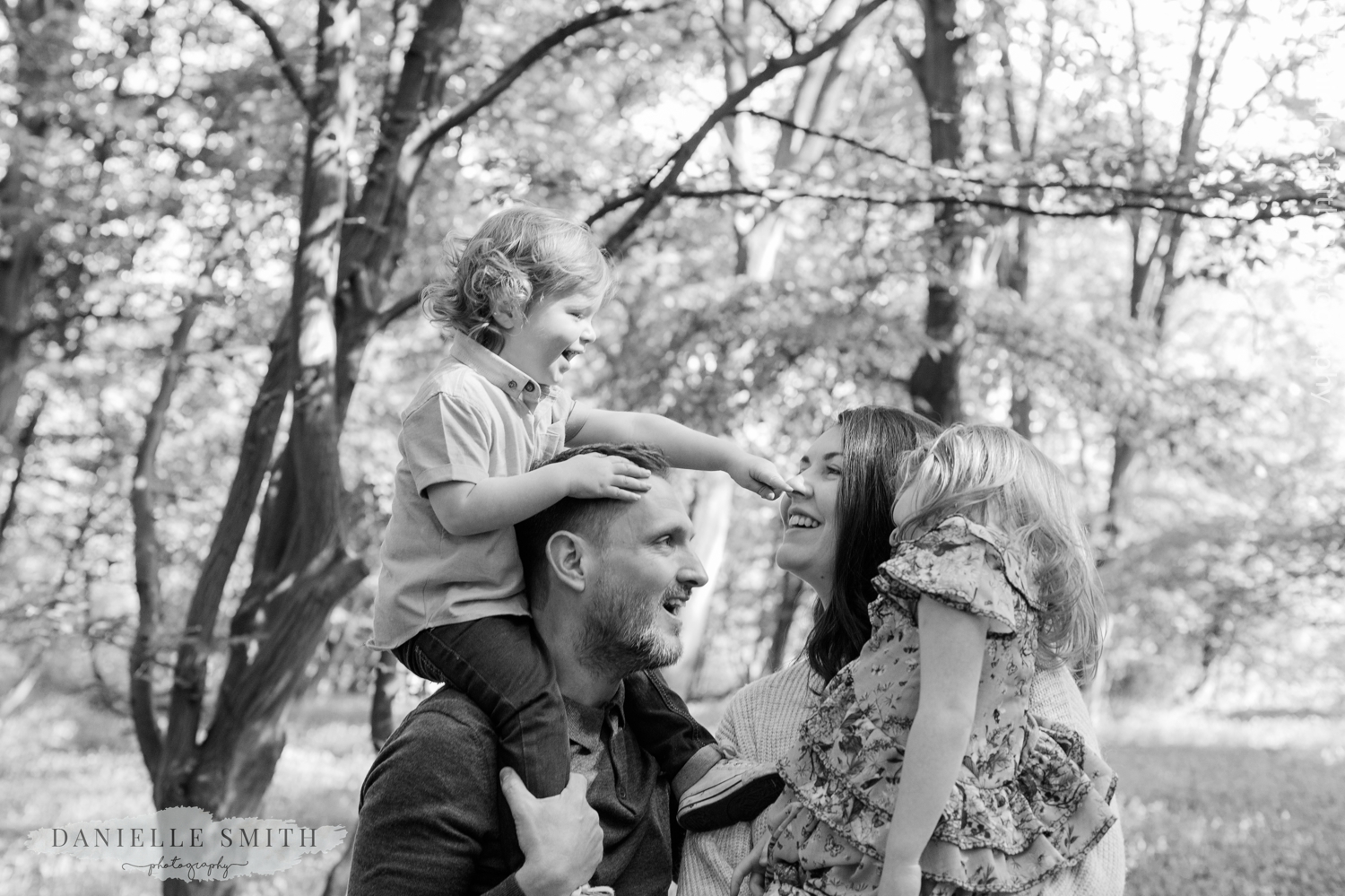 boy pressing mum nose on dads shoulders