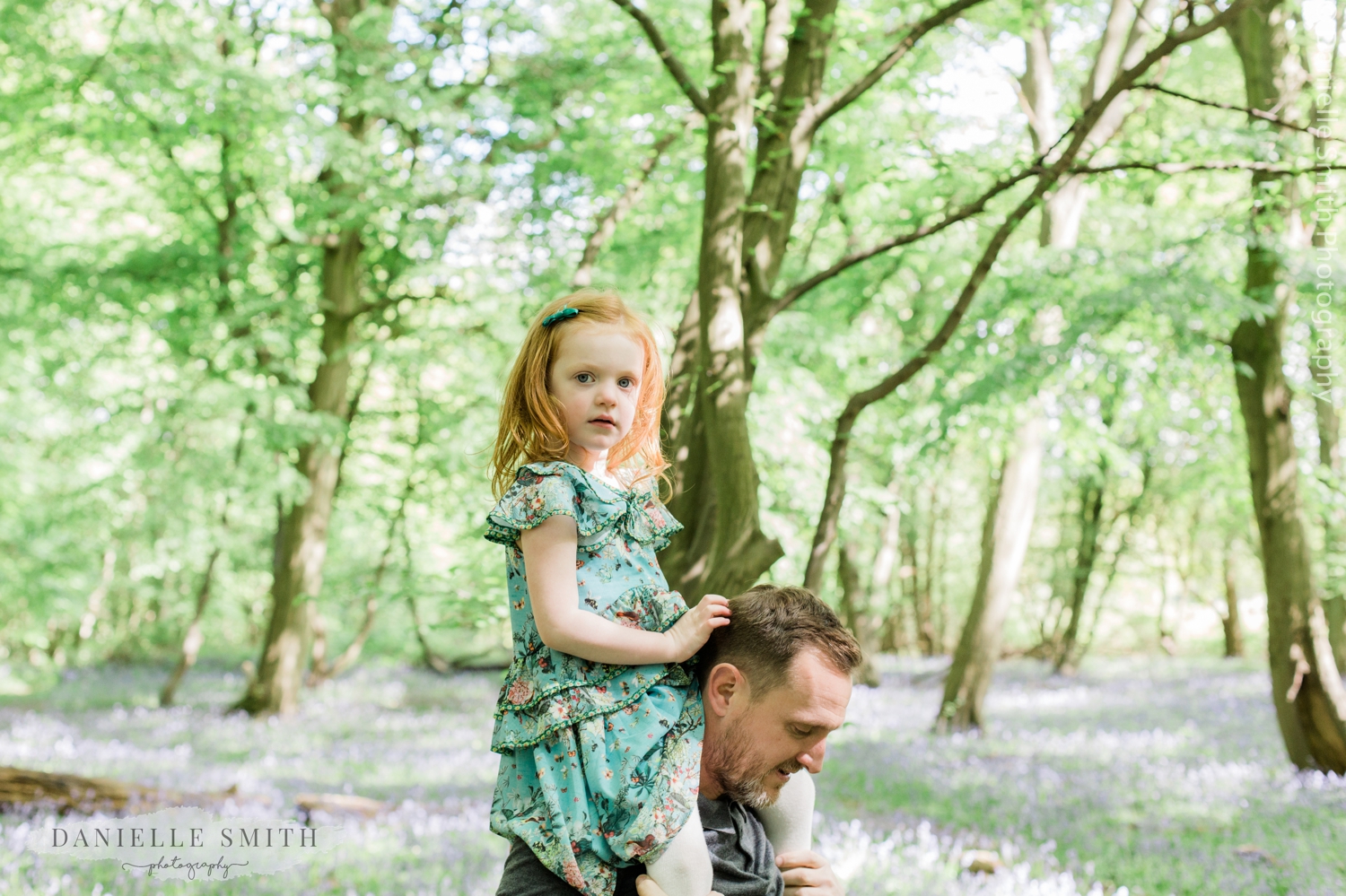 daughter on dads shoulder - family photos with bluebells