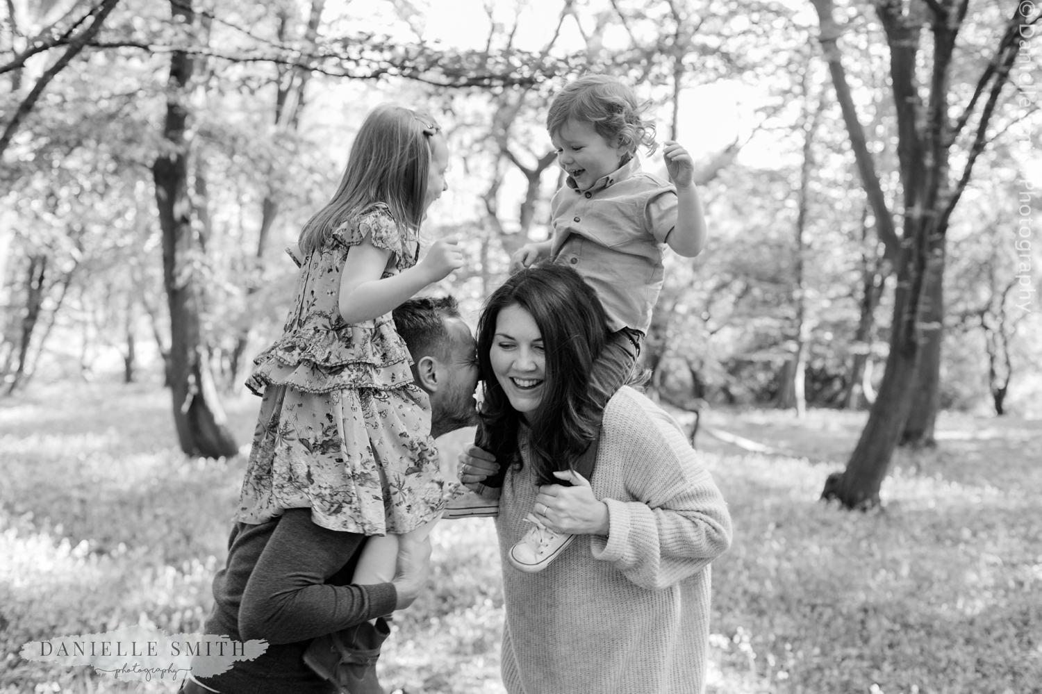 kids on mum and dads shoulder in forest
