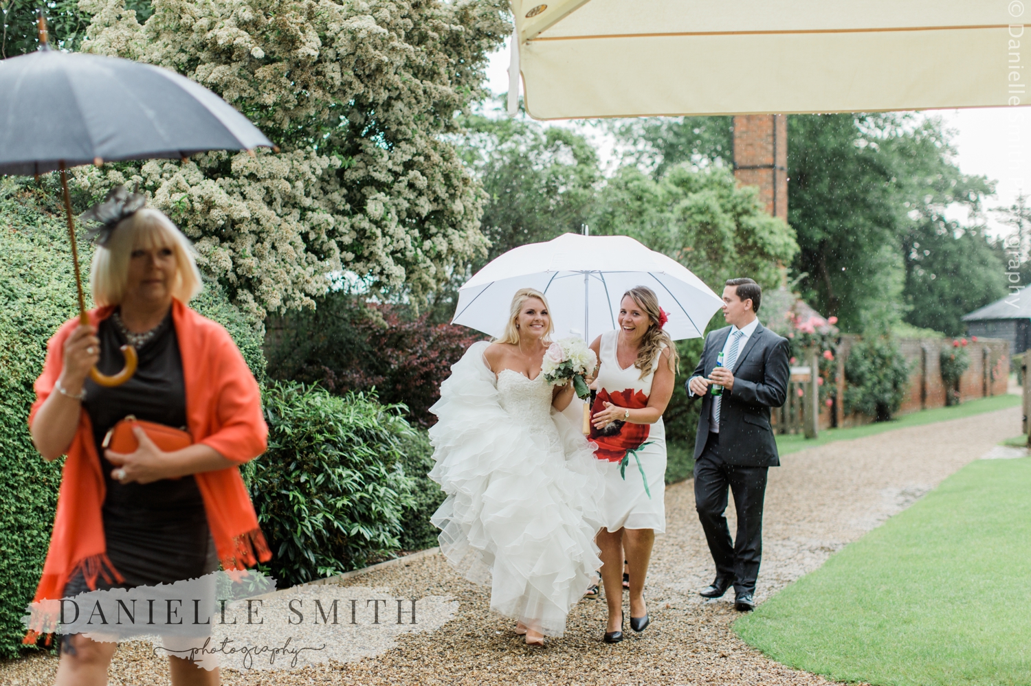 bride walking in rain with umbrella