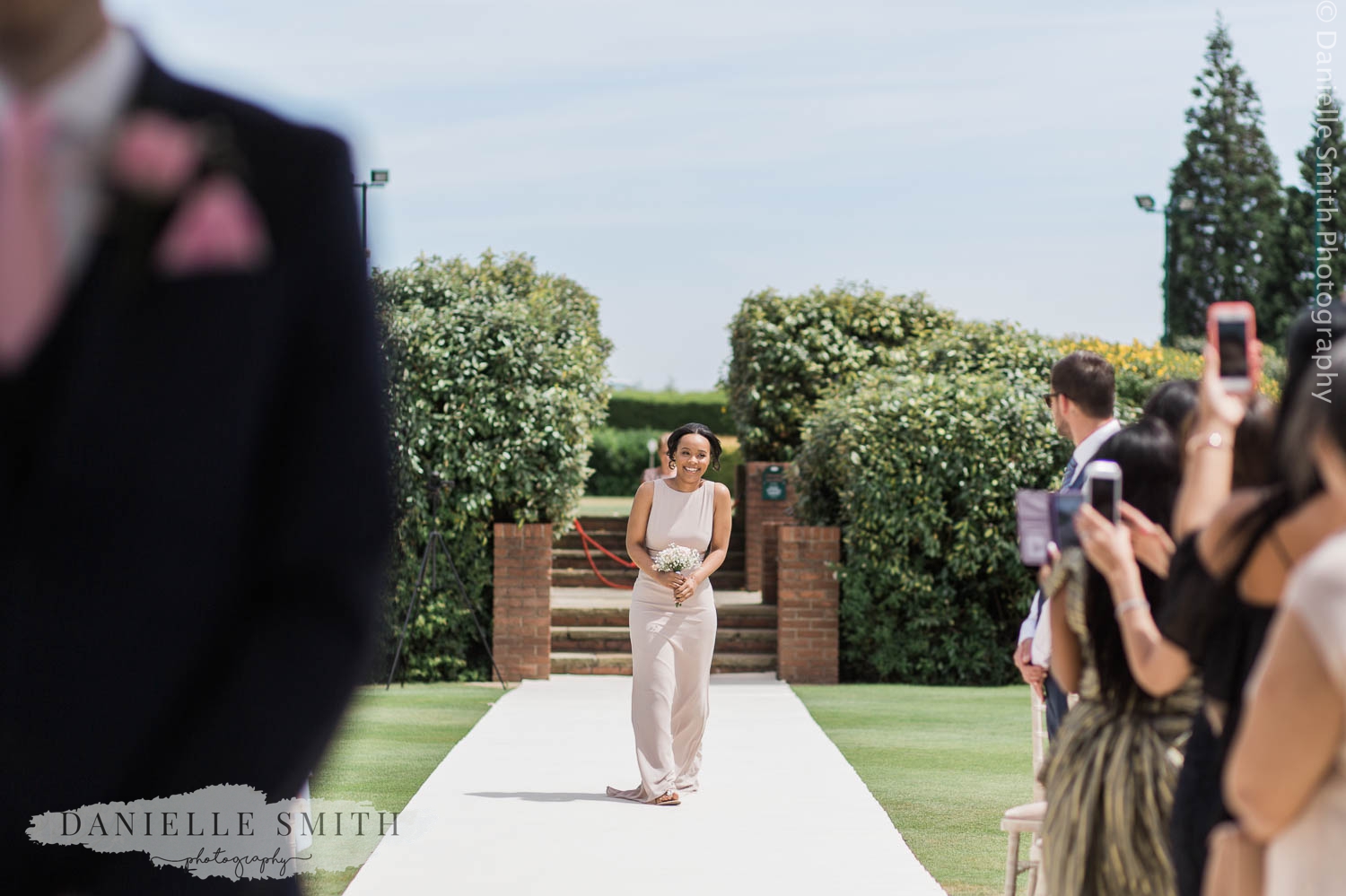 bridesmaid walking down aisle at outdoor wedding in billericay