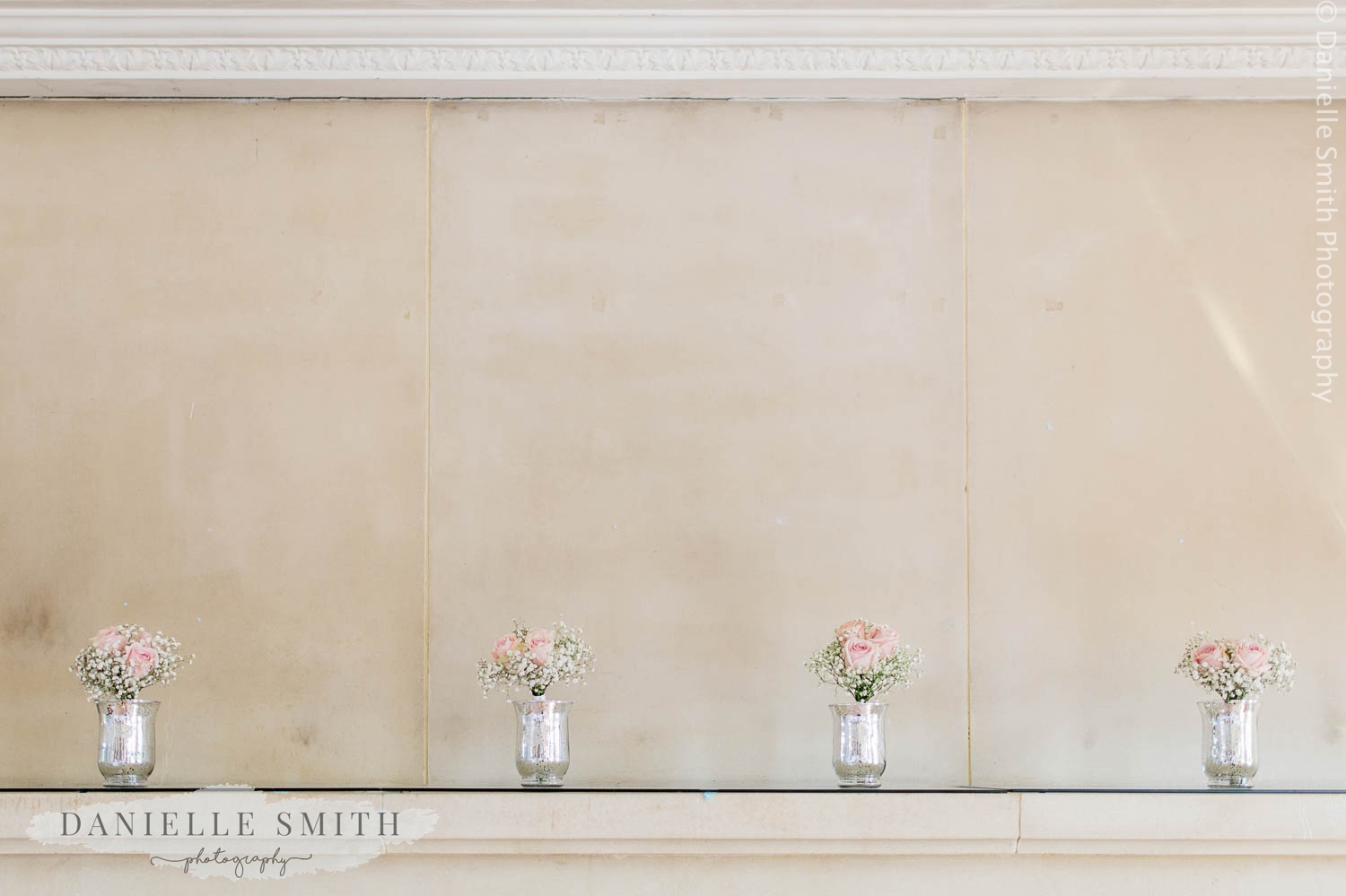 small jars of flowers on fire place at wedding