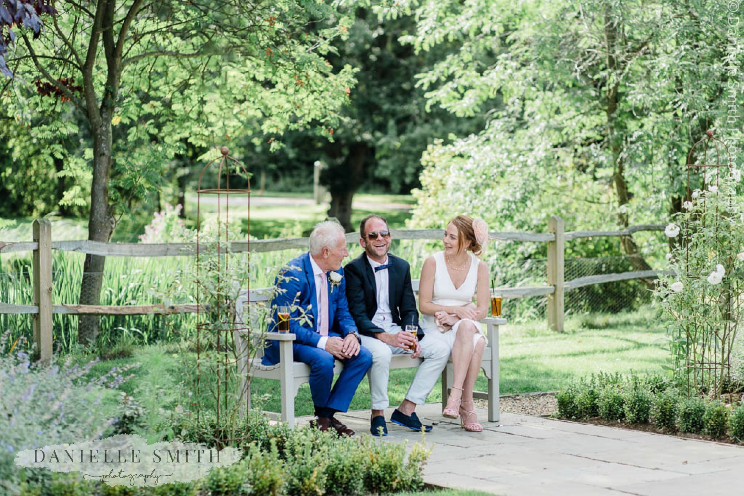 groom and 2 guests sitting on bench in gardens - houchins wedding photography