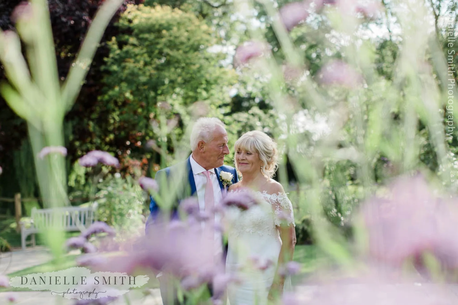 bride and groom smiling through flowers