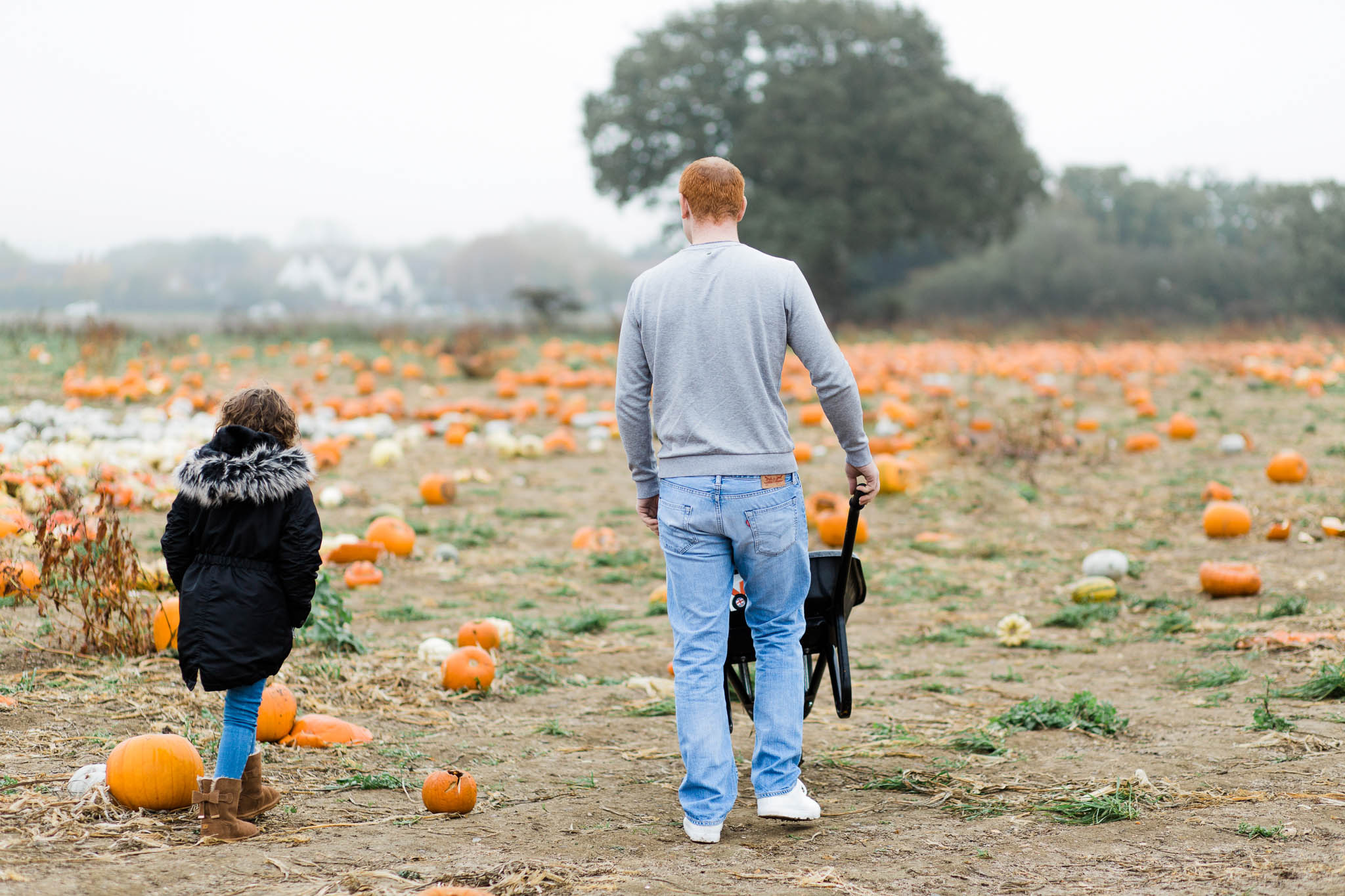 father and daughter walking through pumpkin patch