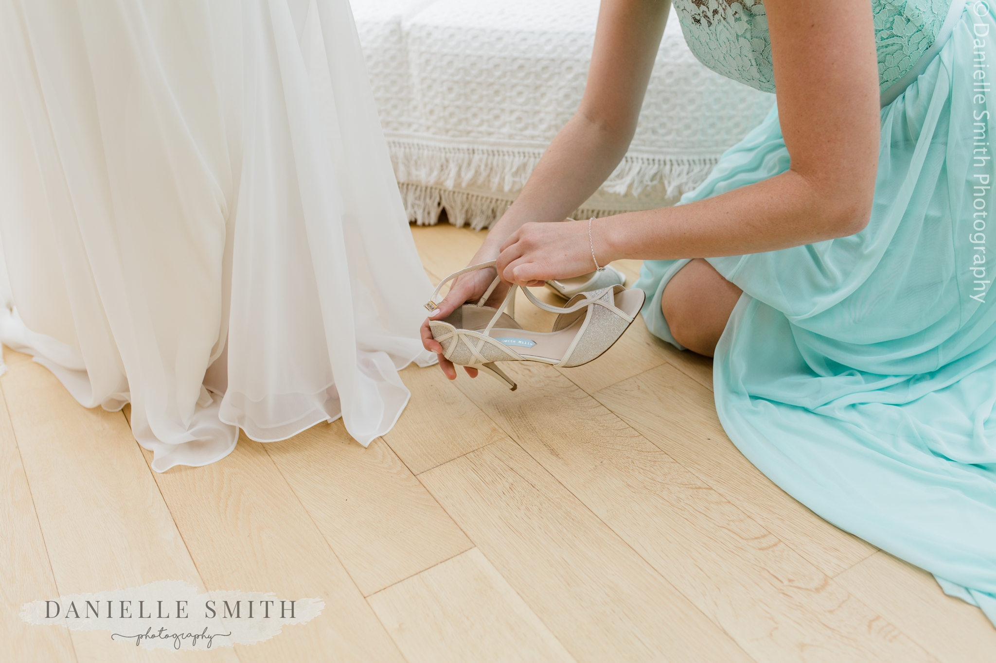 bridesmaid helping bride put her shoes on