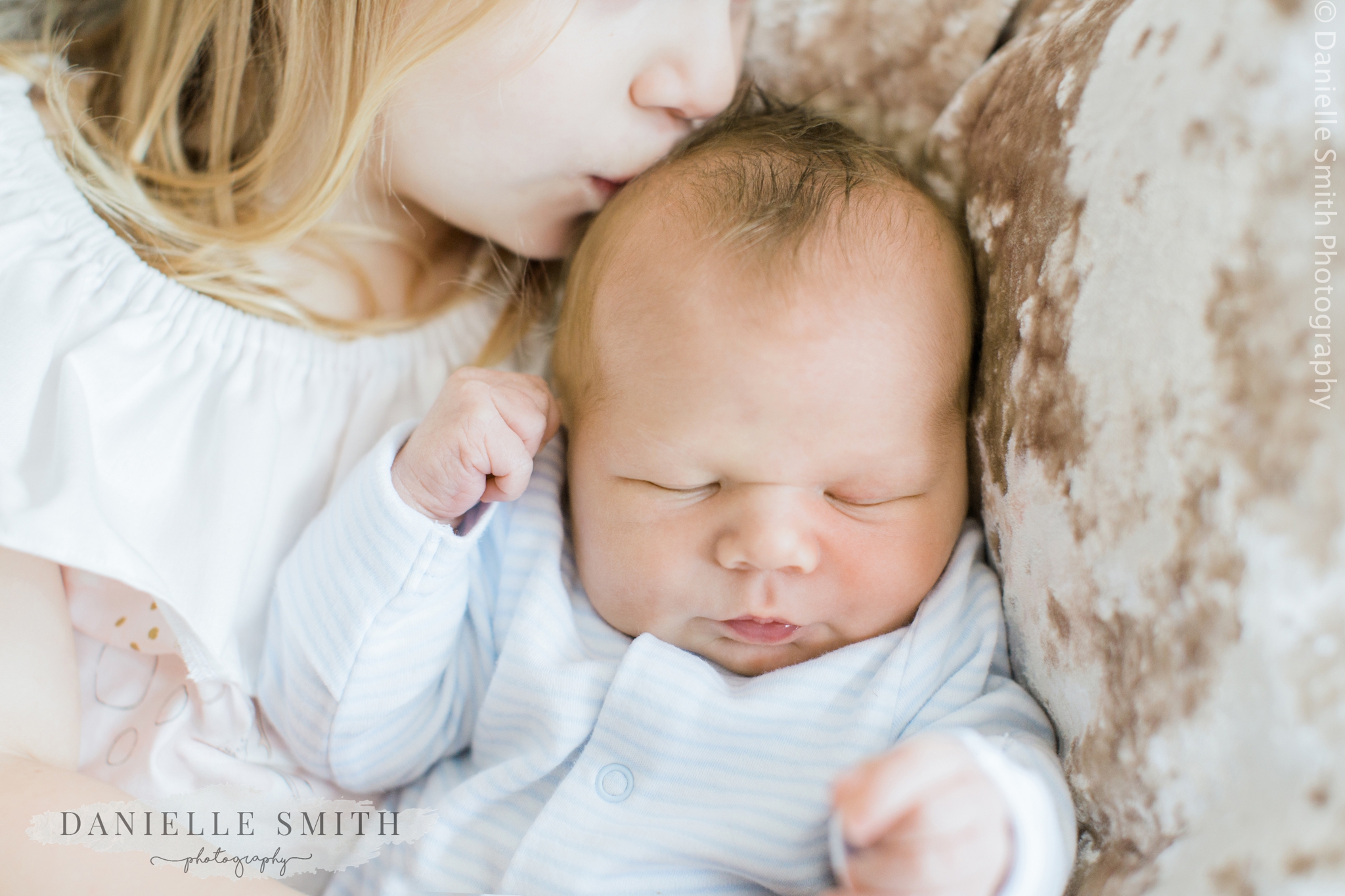 big sister kissing baby brothers head