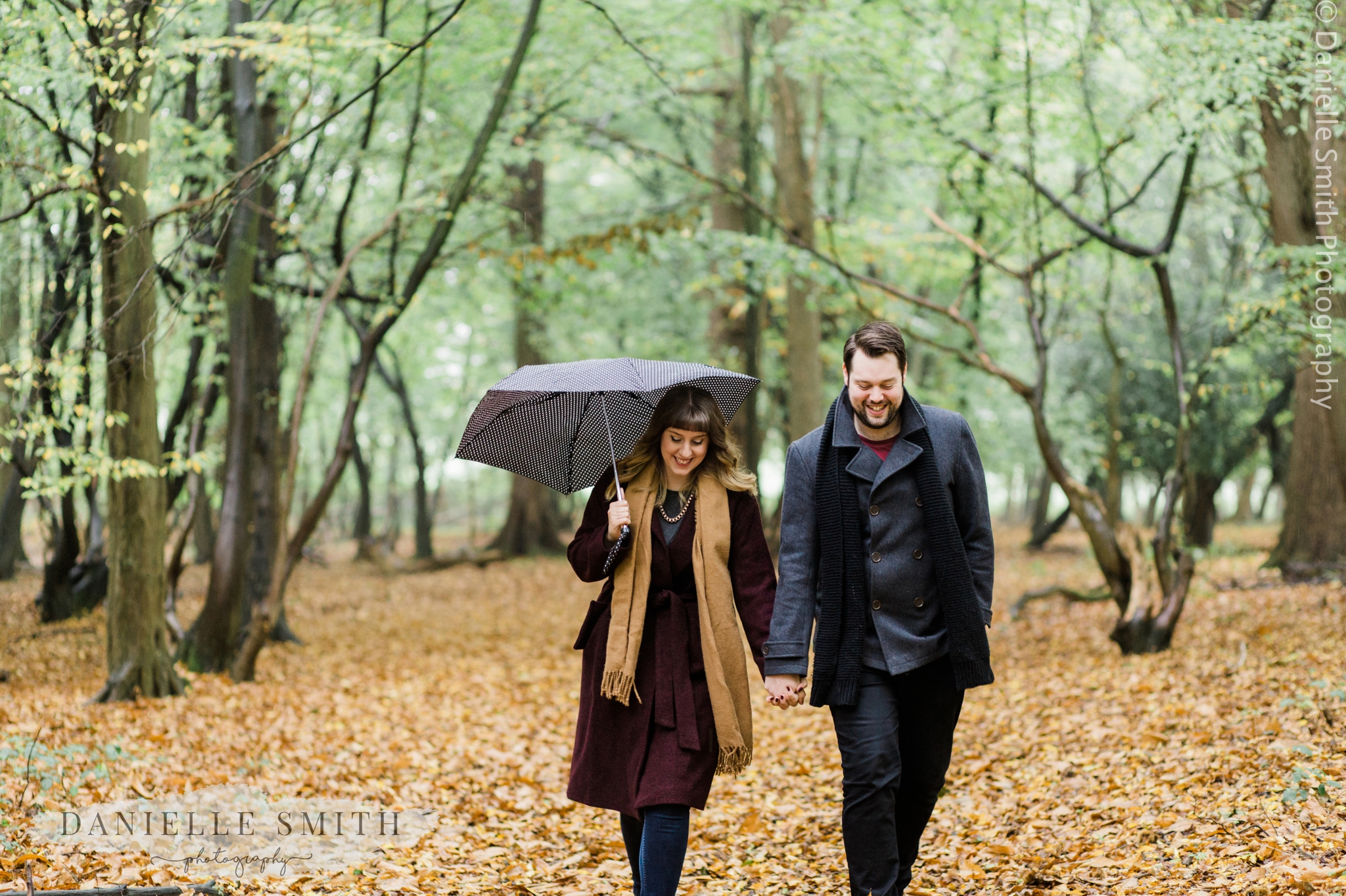 couple walking through woods with umbrella