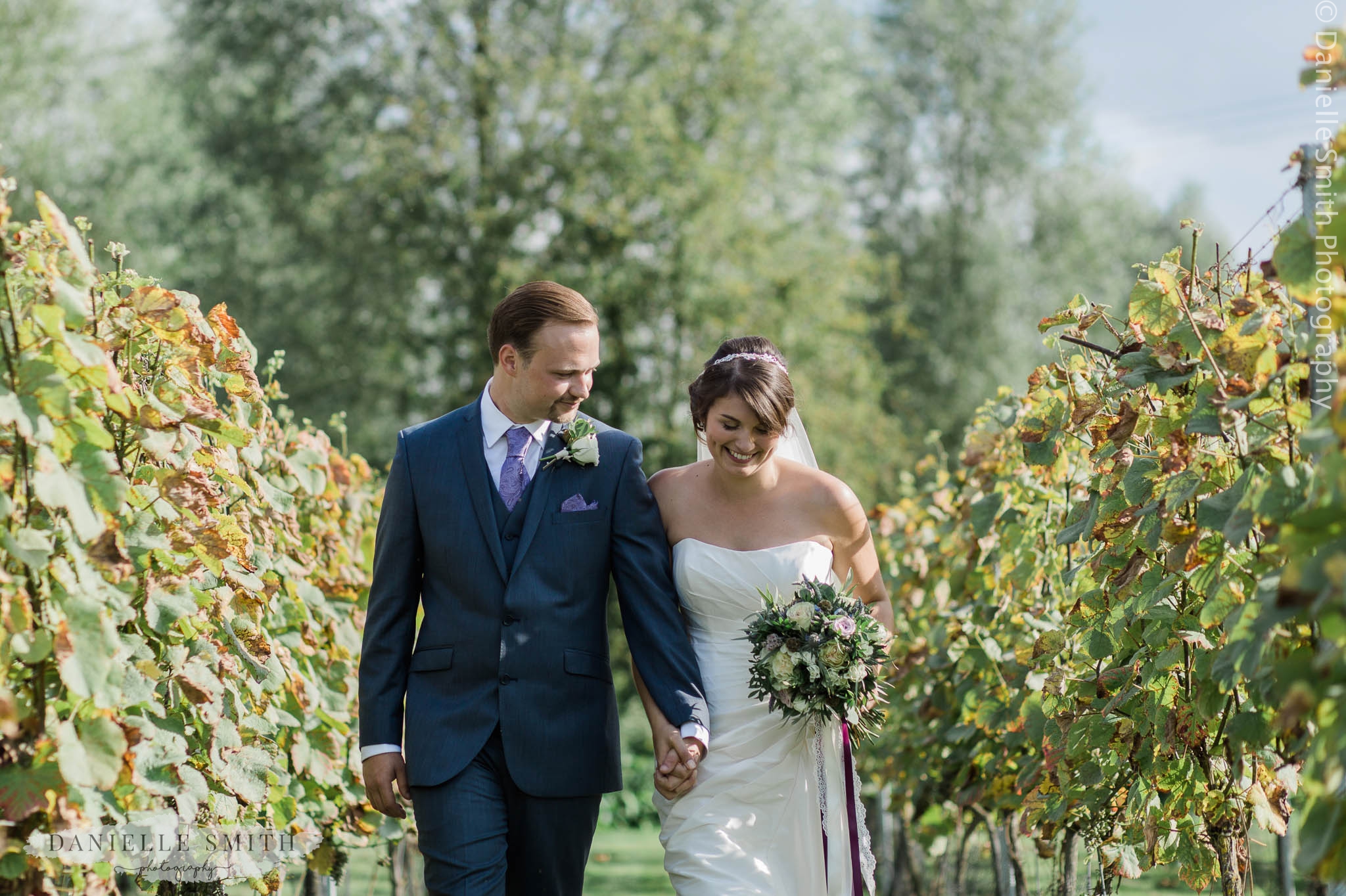 bride and groom walking through vineyard