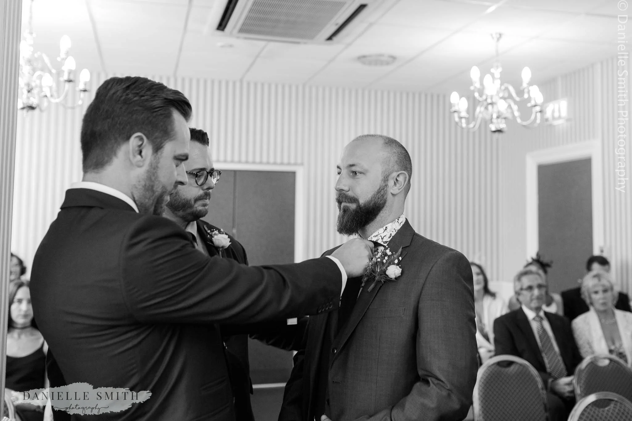 best men helping groom with his tie