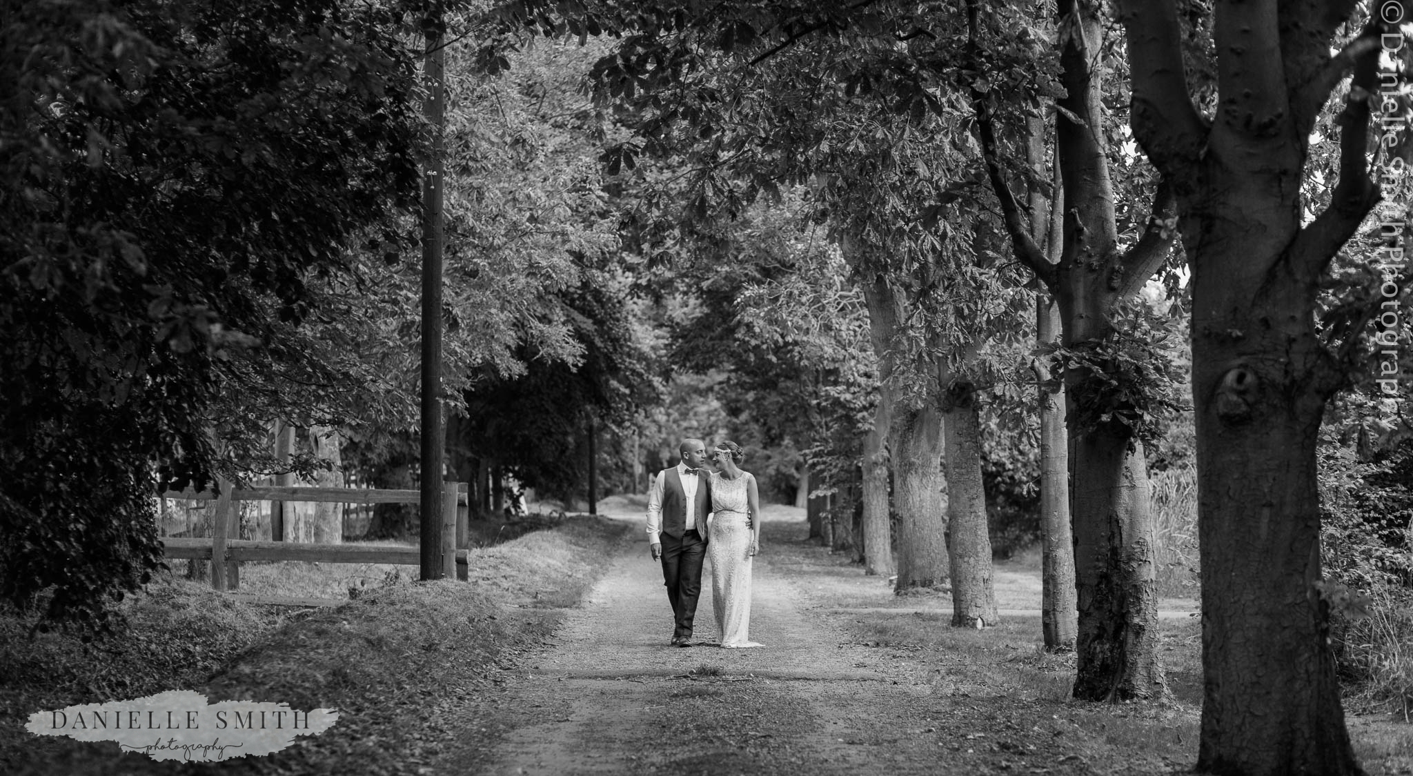 black and white bride and groom walking through trees