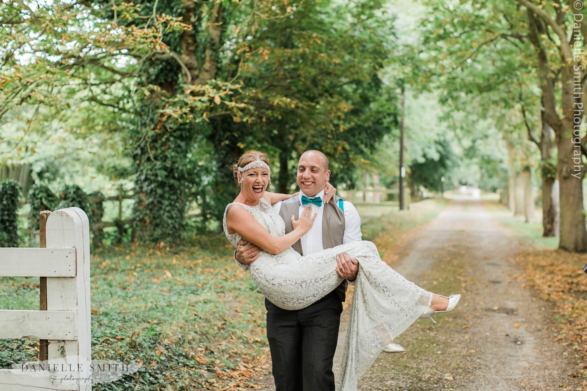 groom picking up bride to cross threshold at gatsby wedding