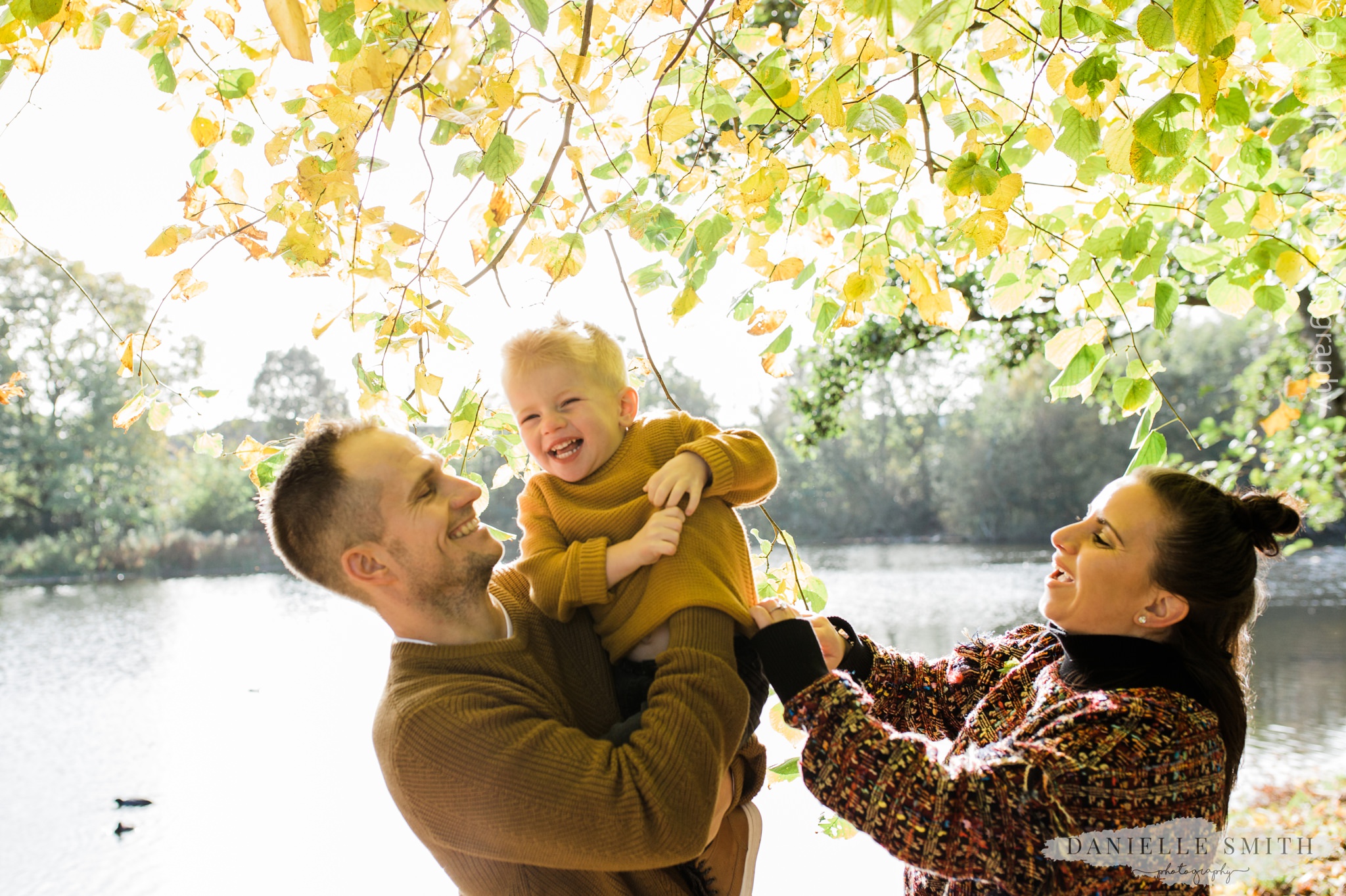 mum dad and son laughing in the park