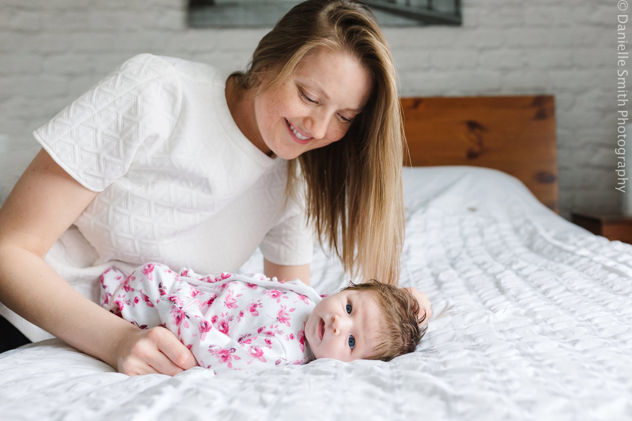 mum looking at her baby girl on bed